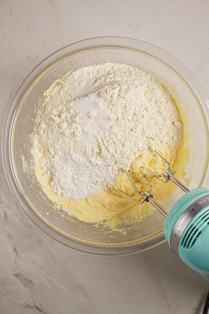 Dry ingredients being added to batter in a glass mixing bowl.