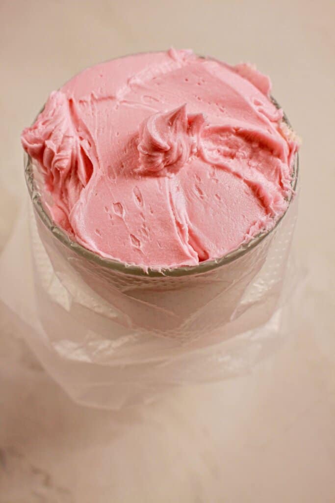 Piping bag being filled with pink frosting.