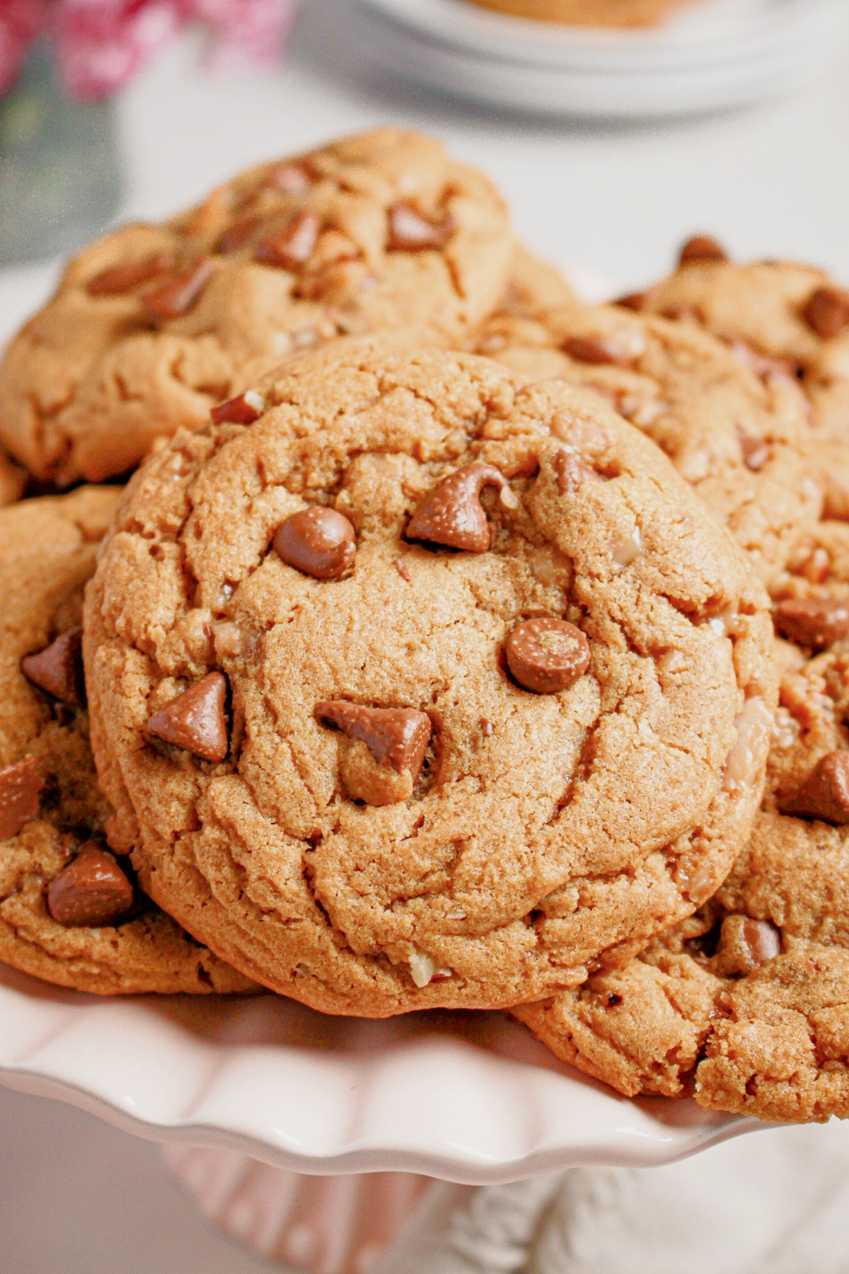 Peanut butter chocolate chip cookies stacked on a cake plate.