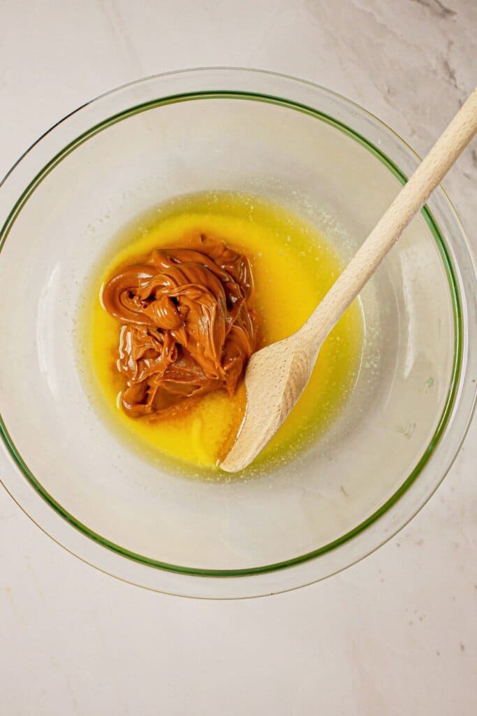 Peanut butter and butter being melted in a glass bowl.