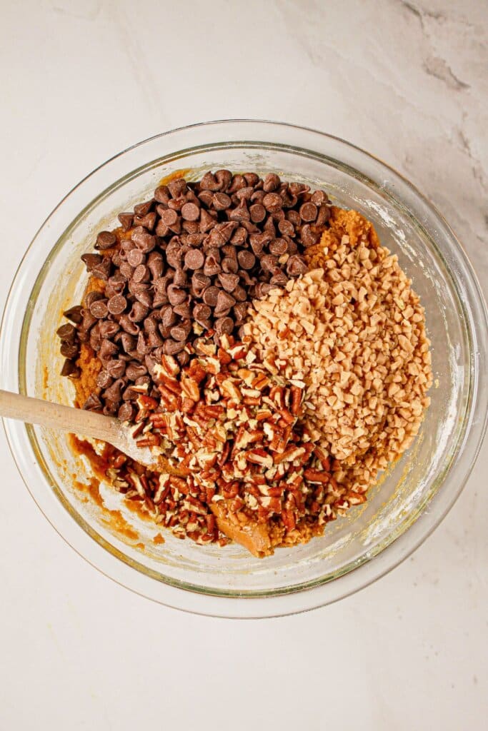 Toffee bits and pecans being folded into dough.