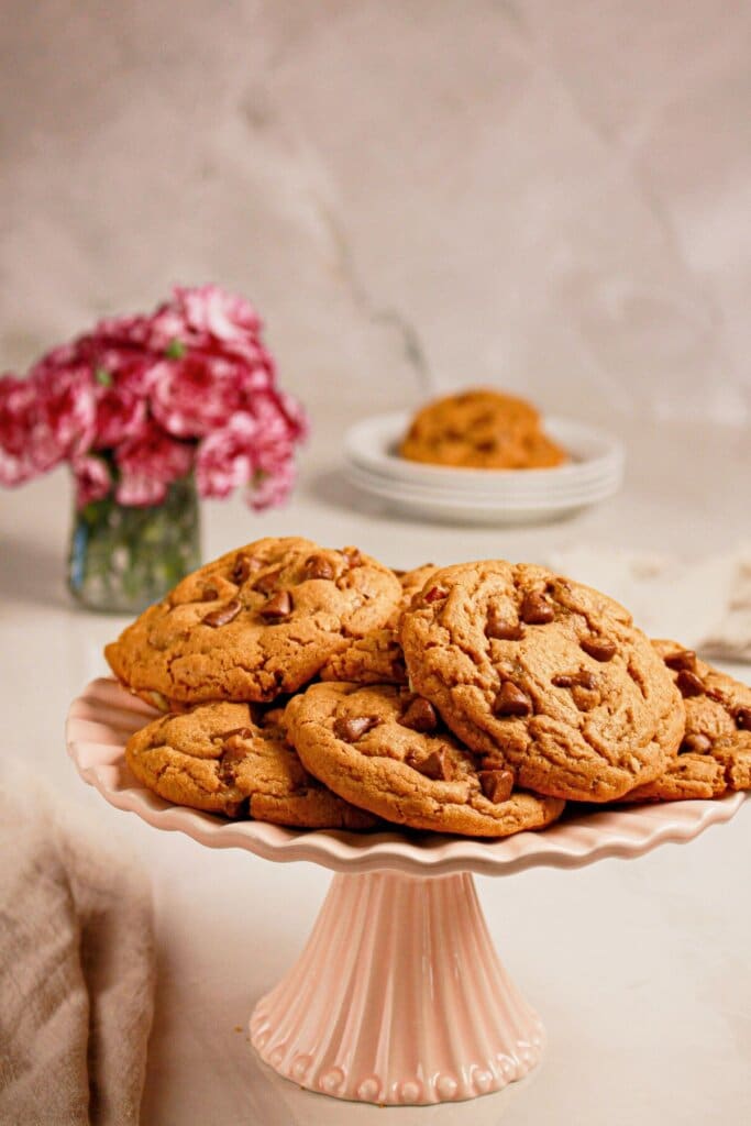 Peanut butter chocolate chip cookies stacked on a cake plate.