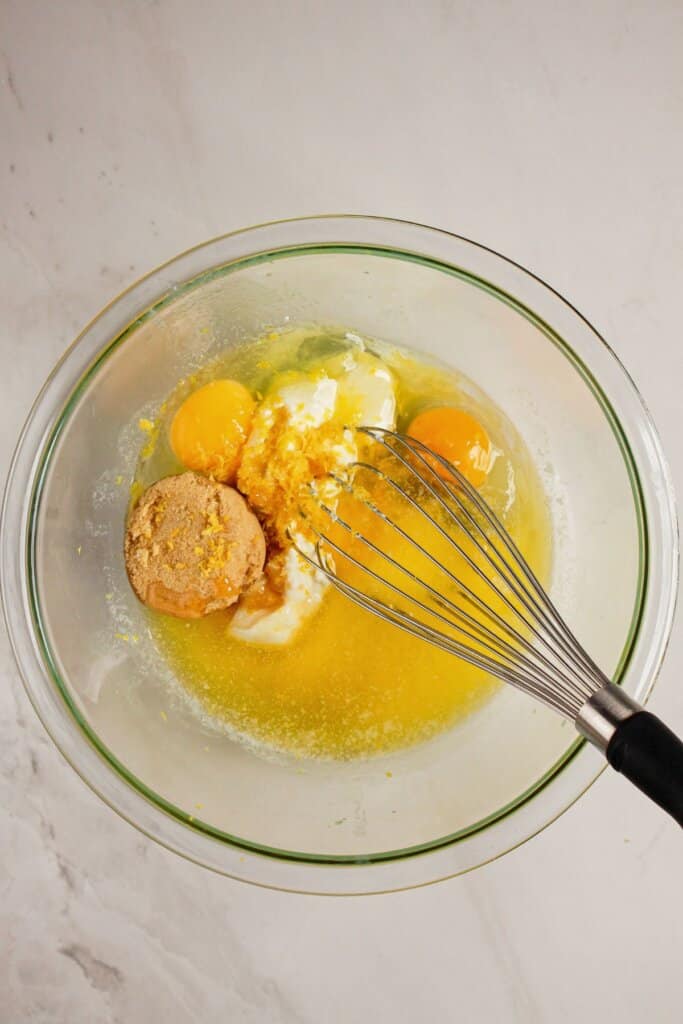 Wet ingredients being mixed in a glass mixing bowl.