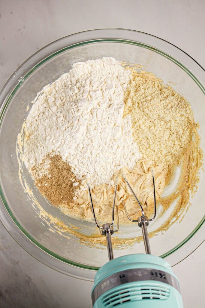 Dry ingredients being mixed into dough in a glass bowl.