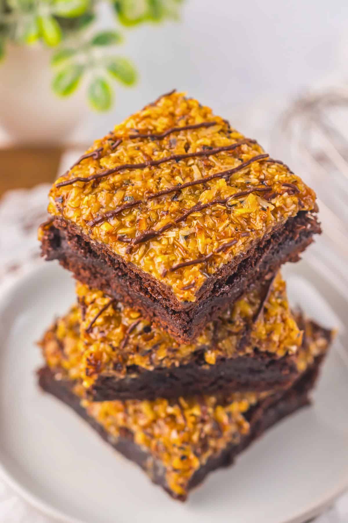 Three brownies stacked on top of each other on a small plate.