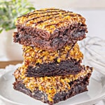 Three brownies stacked on top of each other on a small plate.