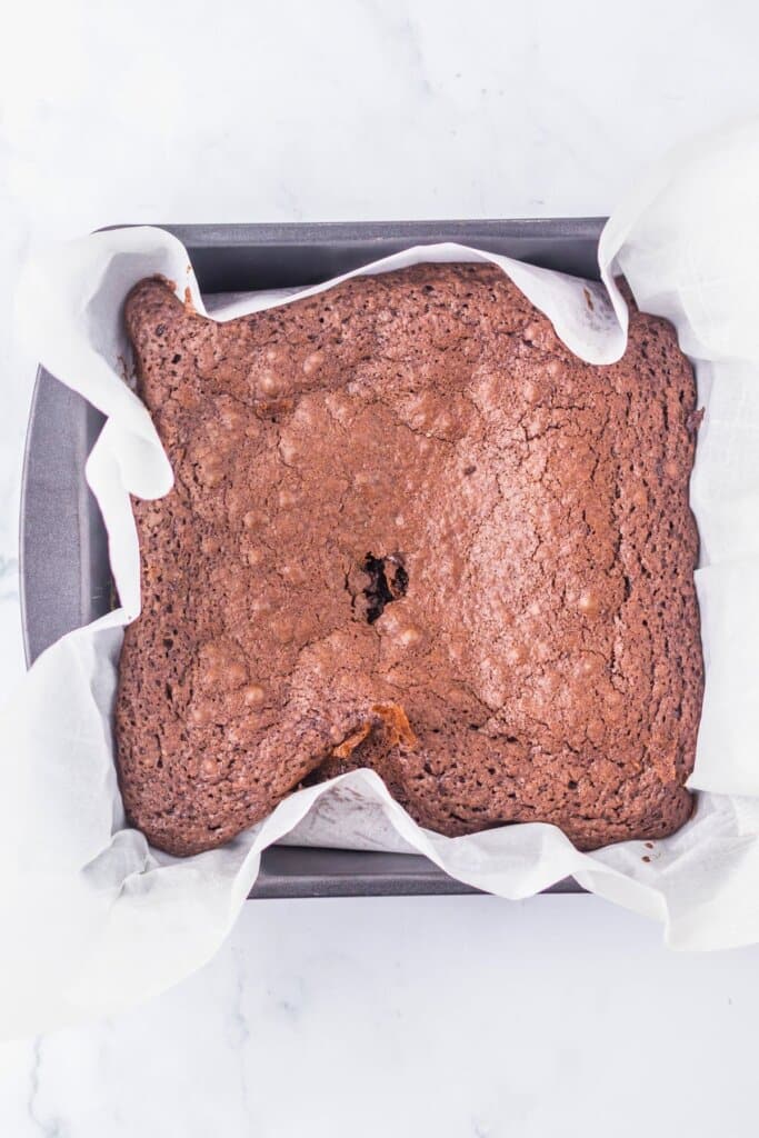 Brownies cooling in a parchement lined baking pan.