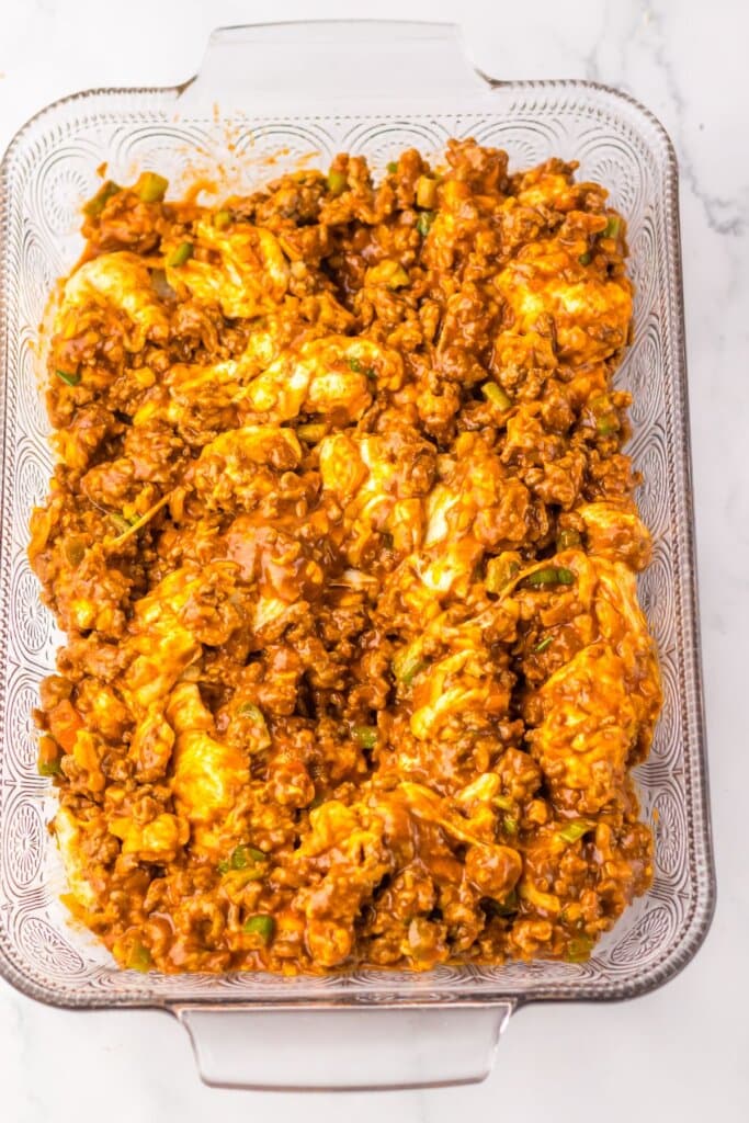 Dough and beef mixture in a glass baking dish.