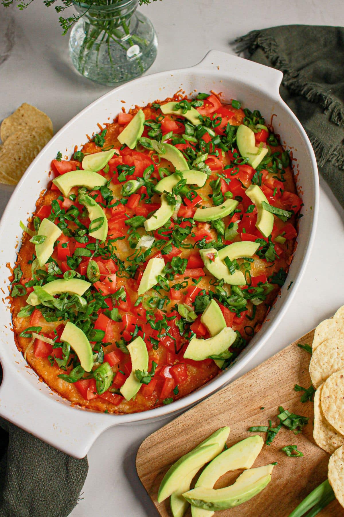 Tomatoes and avocados on top of melted cheese in a baking dish.