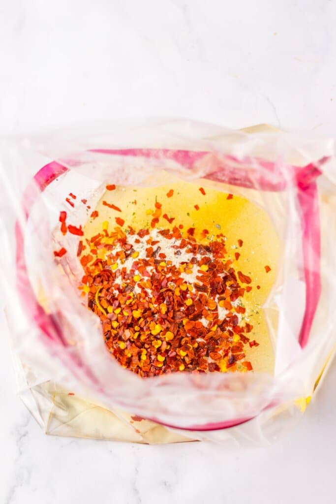 Seasonings and oil being mixed in a storage bag.