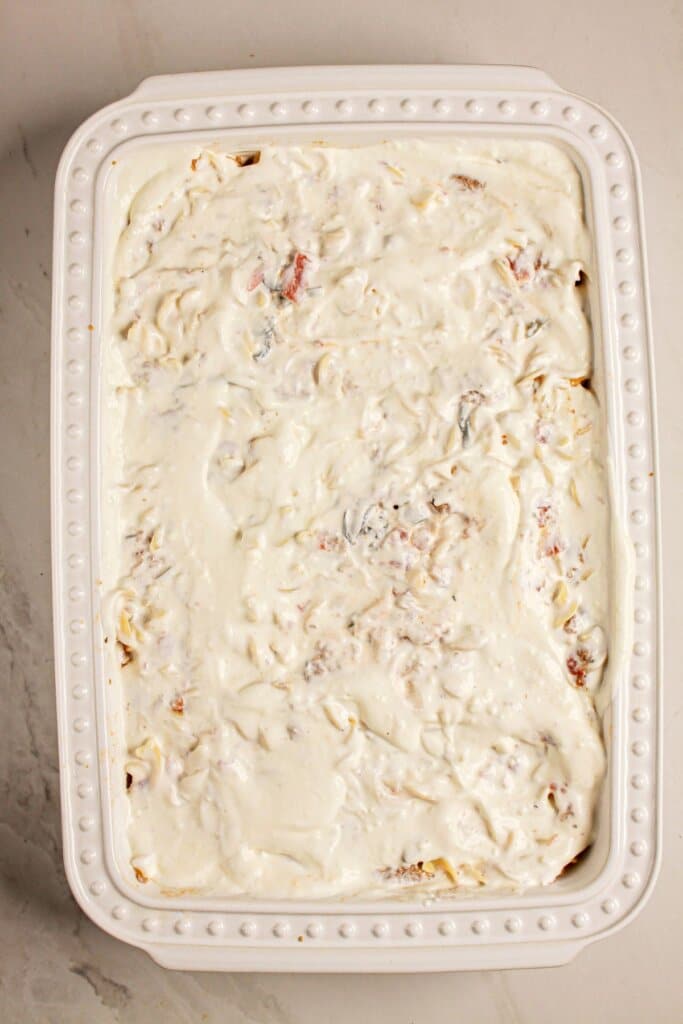 Sour cream mixture being spread on top of meat and veggie mixture.