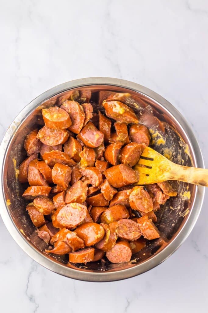 Smoked sausage and being mixed in a bowl.