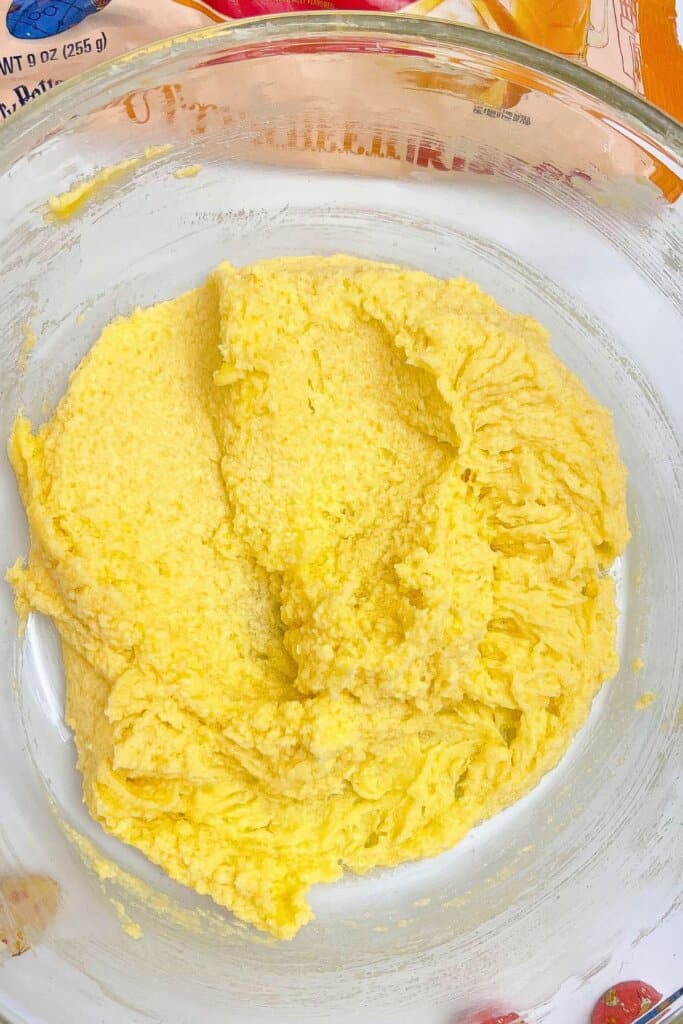 Eggs and vanilla being added to dough in a glass mixing bowl.
