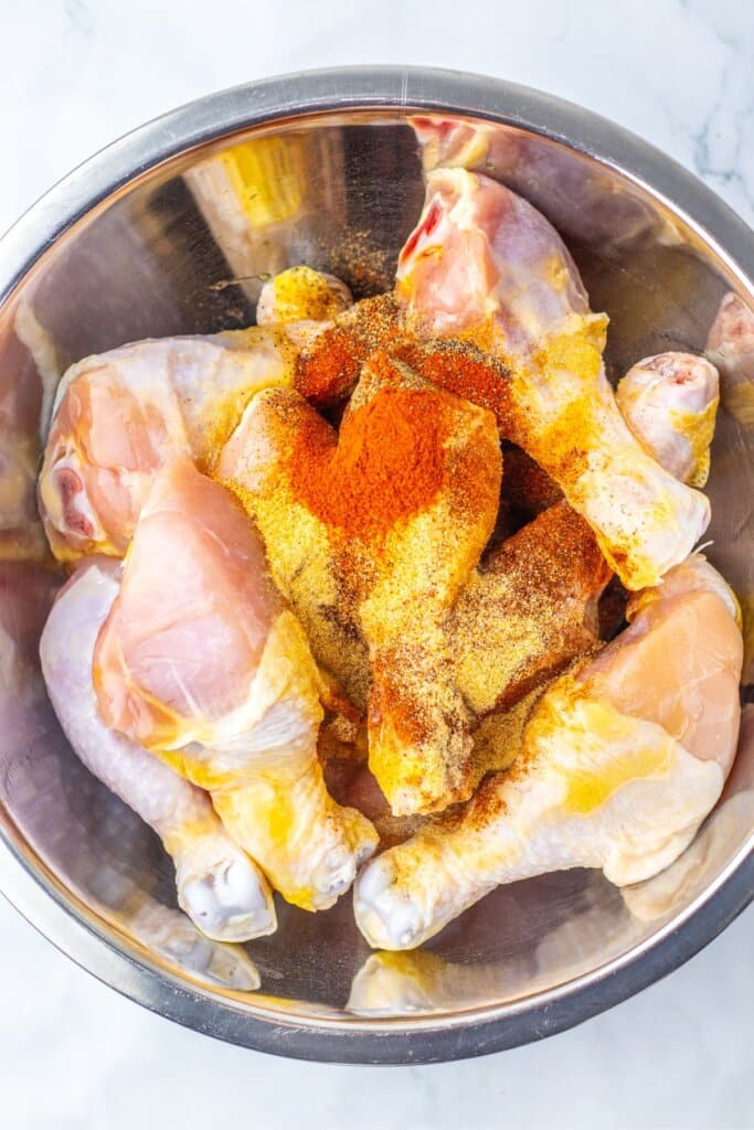 Drumsticks being seasoned in a large mixing bowl.