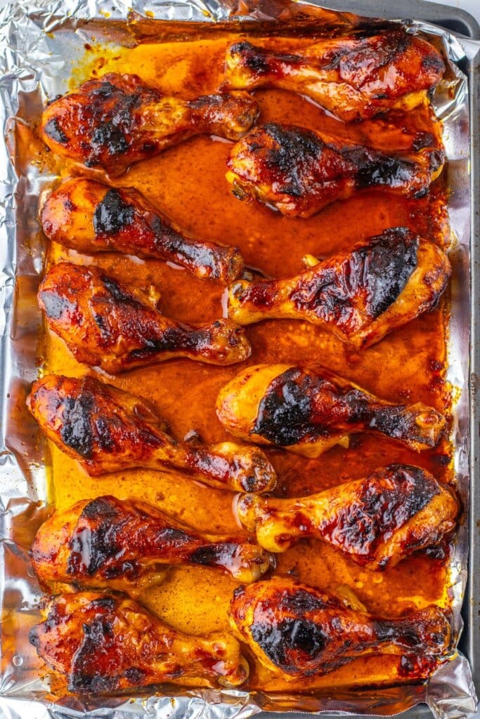 Baked drumsticks cooling on a foil lined baking sheet.
