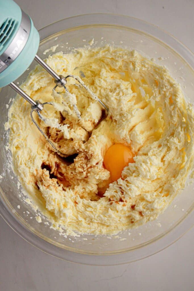 Butter, eggs, and vanilla being mixed in a glass bowl.