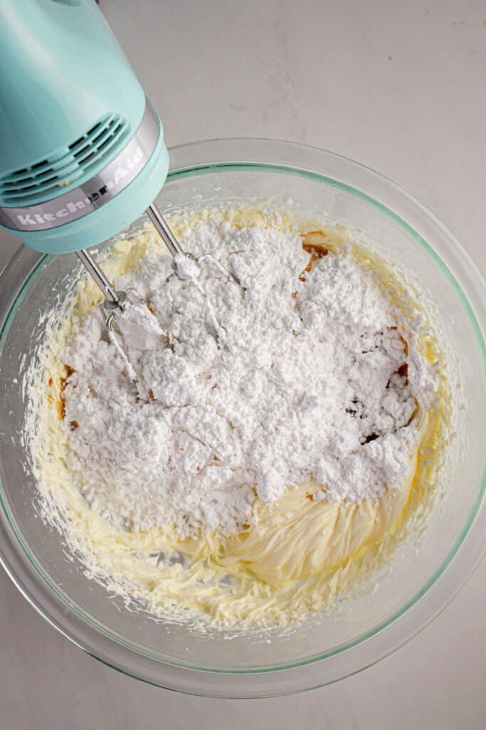 Dry ingredients being added to batter in a glass bowl.