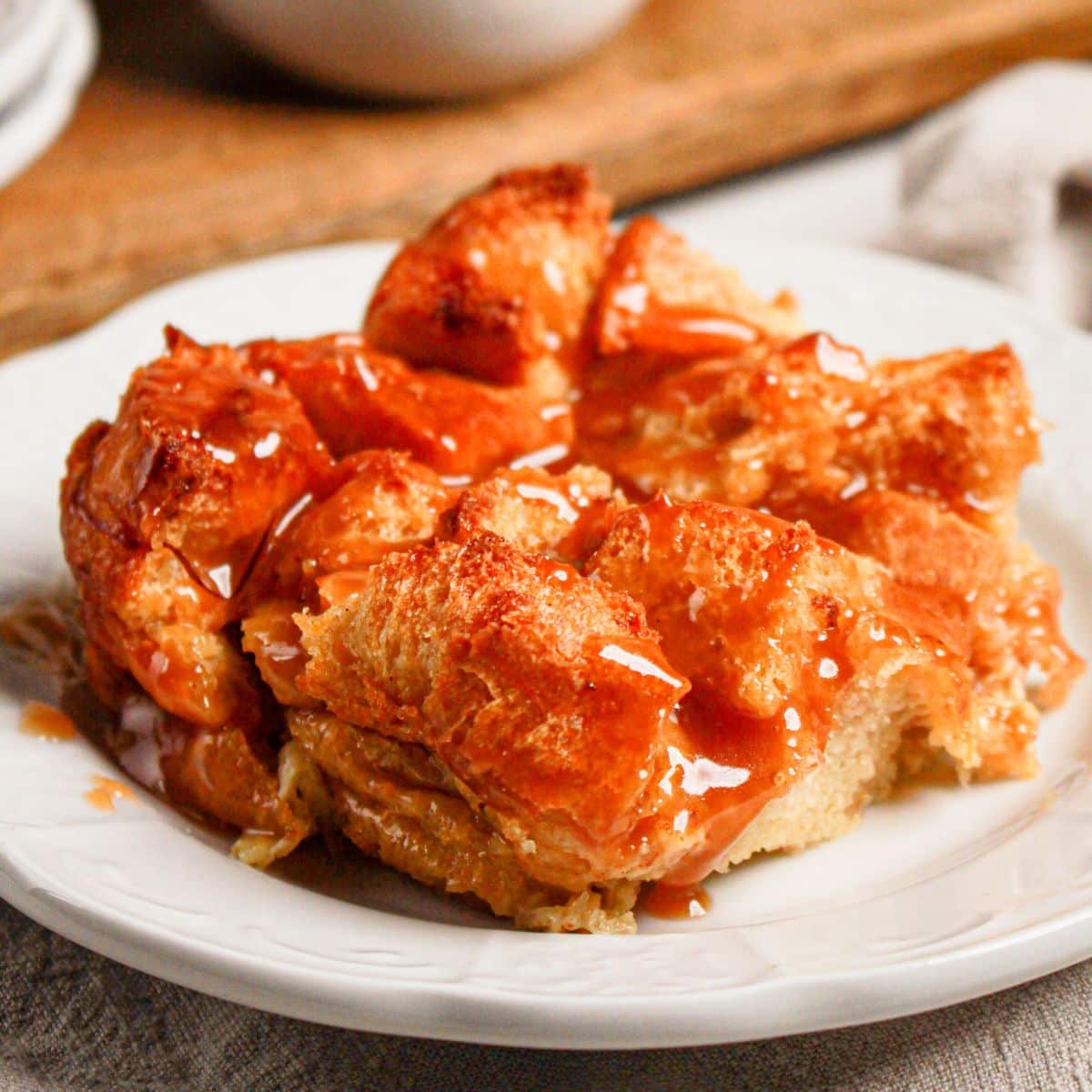 Serving of caramel bread pudding on a white plate.