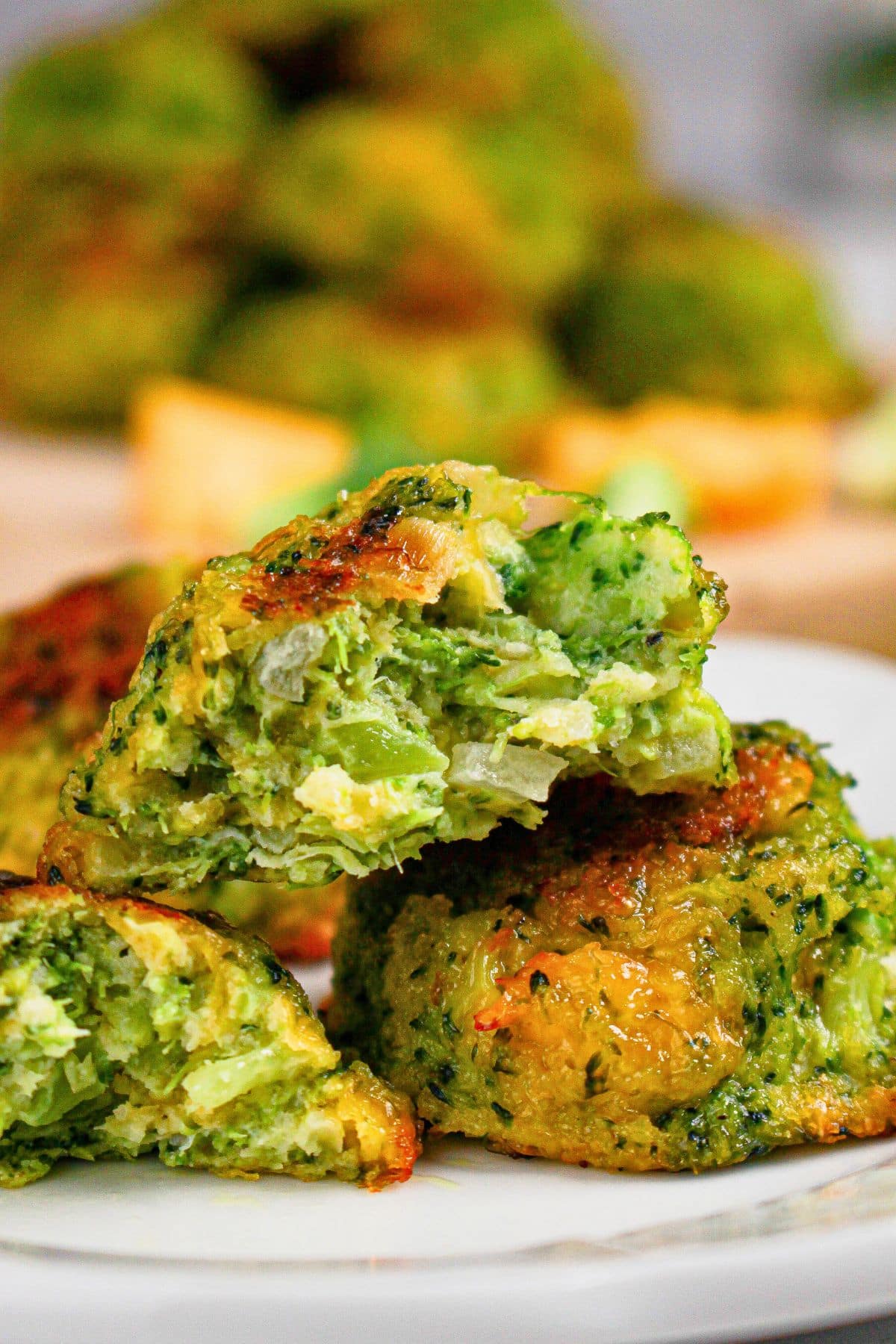 Three cheesy broccoli bites on a plate.