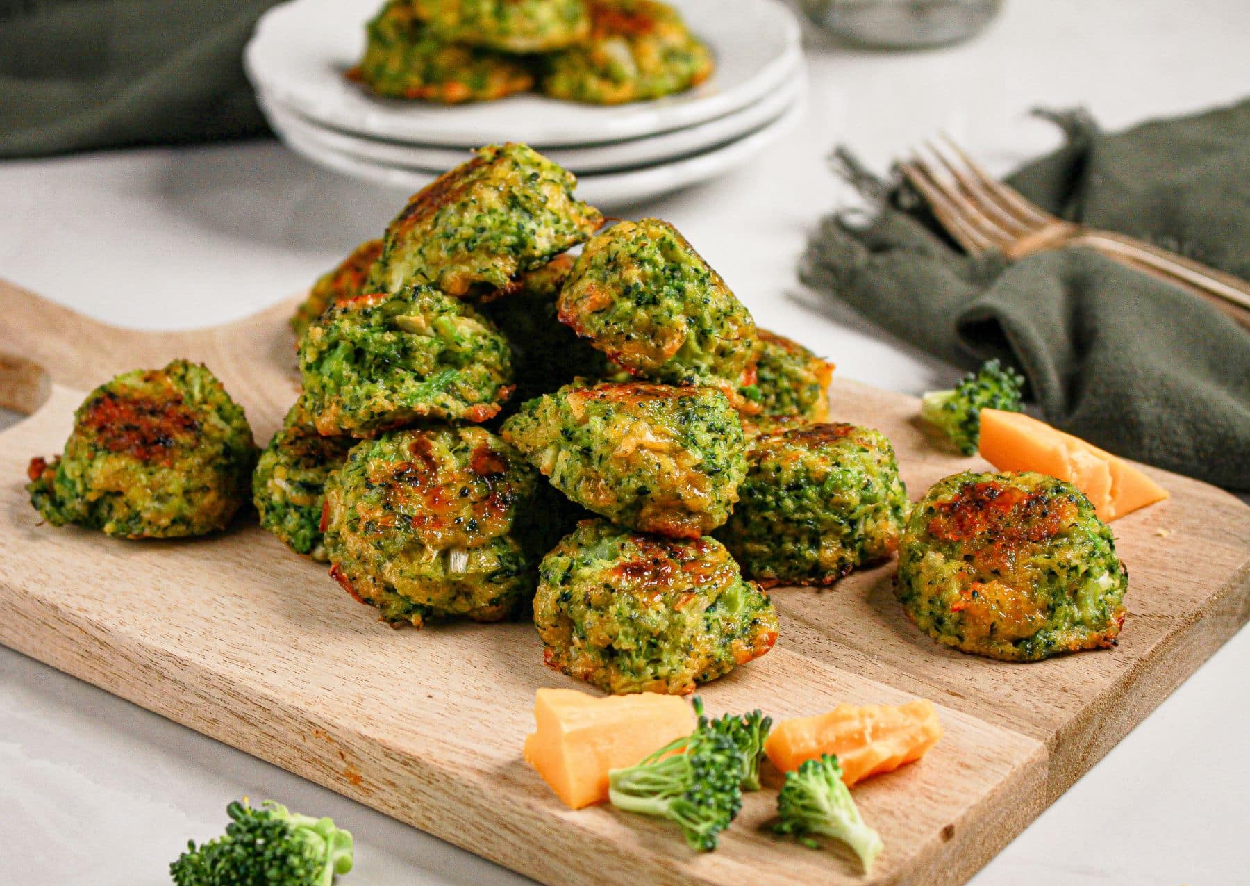 Cheesy broccoli bites on a wooden cutting board.