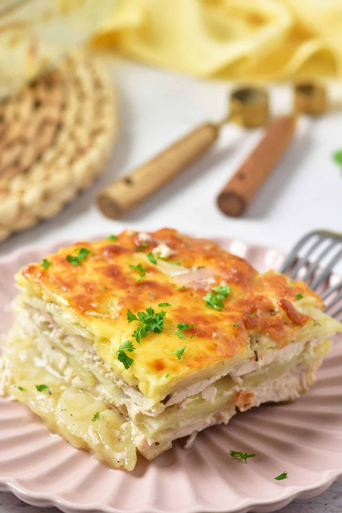 Slice of cheesy chicken potato bake on a pink plate.
