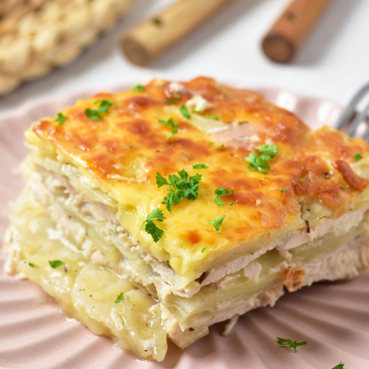 Slice of cheesy chicken potato bake on a pink plate.