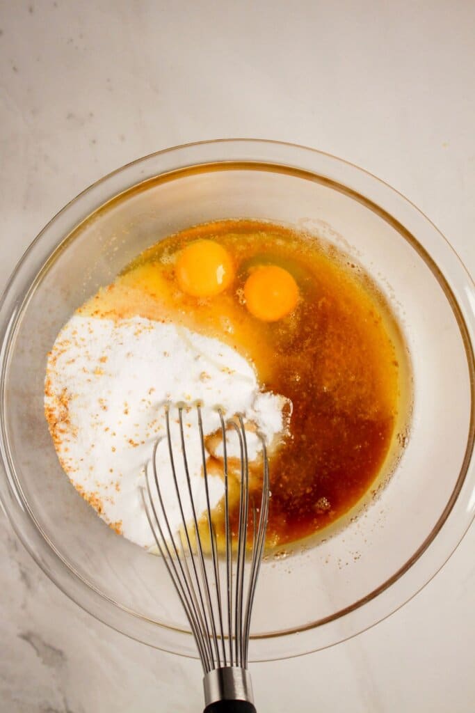 Wet ingredients being mixed into a glass bowl.