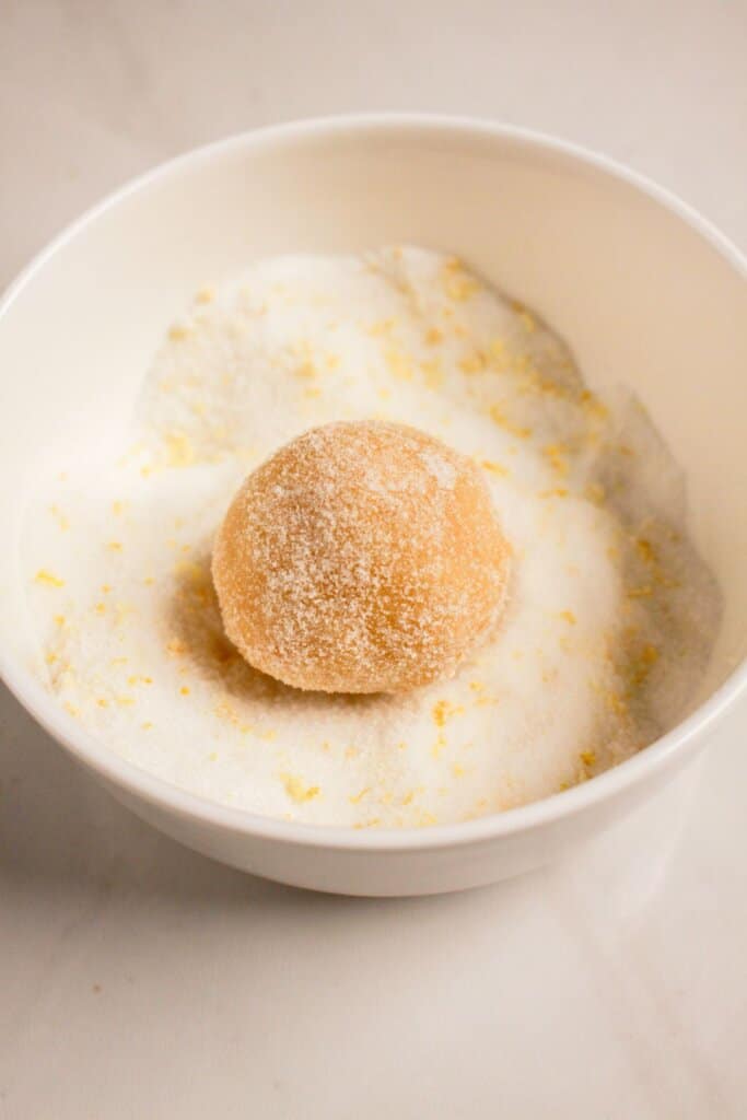 Dough being rolled in citrus sugar.