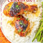 Two cajun chicken legs on a white plate with rice and green beans.