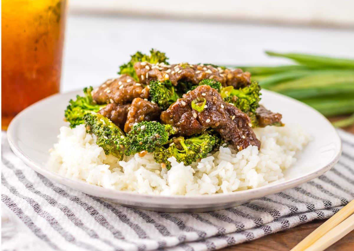 White plate with rice topped with beef and broccoli.