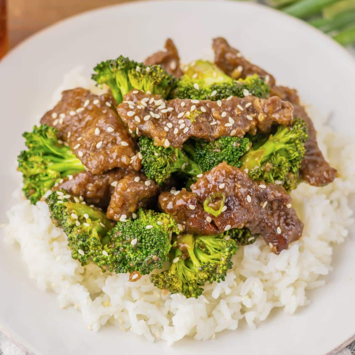 White plate with rice topped with beef and broccoli.