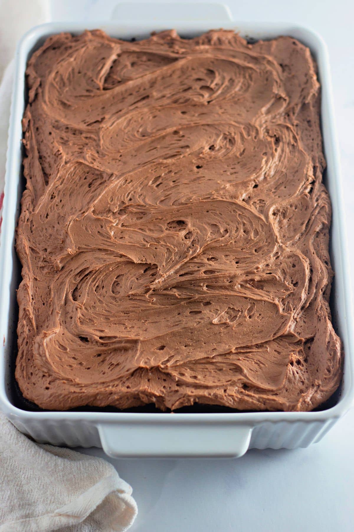 Whole chocolate cake in a white baking dish.