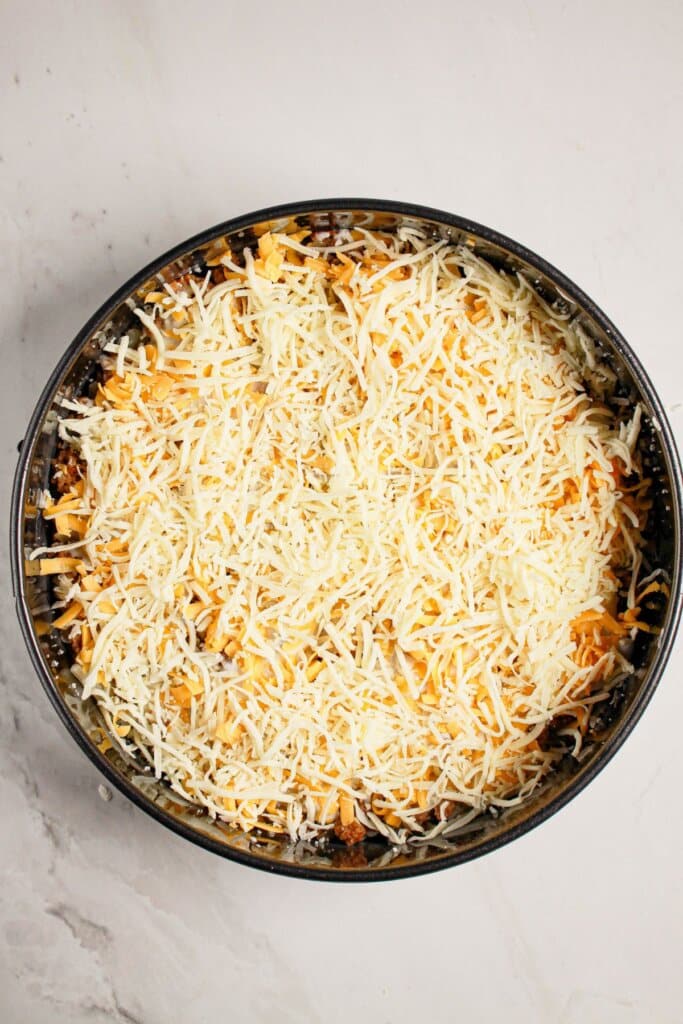 Cheese being sprinkled on top of springform pan.