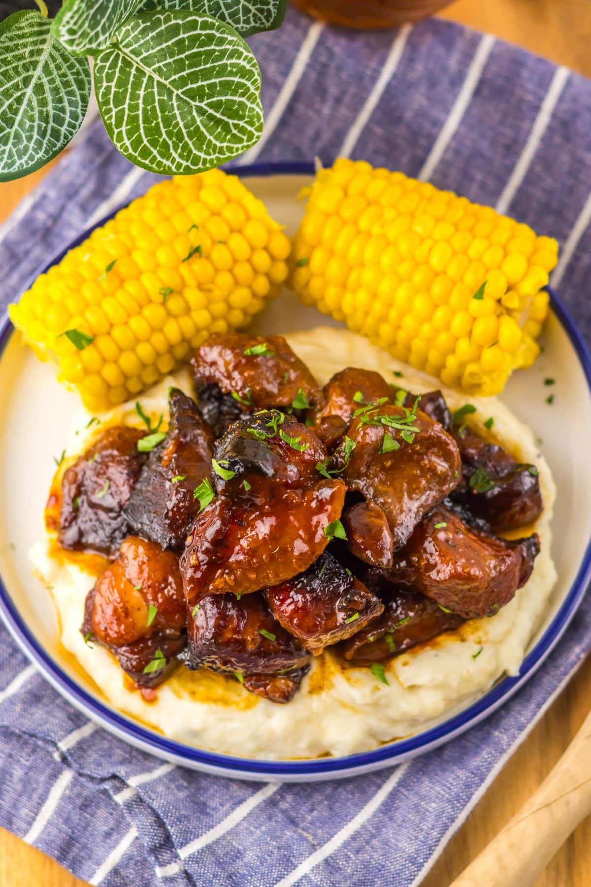 Plate full of bbq riblets on top of mashed potatoes and corn on the cob.