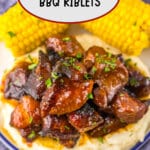 Plate full of bbq riblets on top of mashed potatoes and corn on the cob.