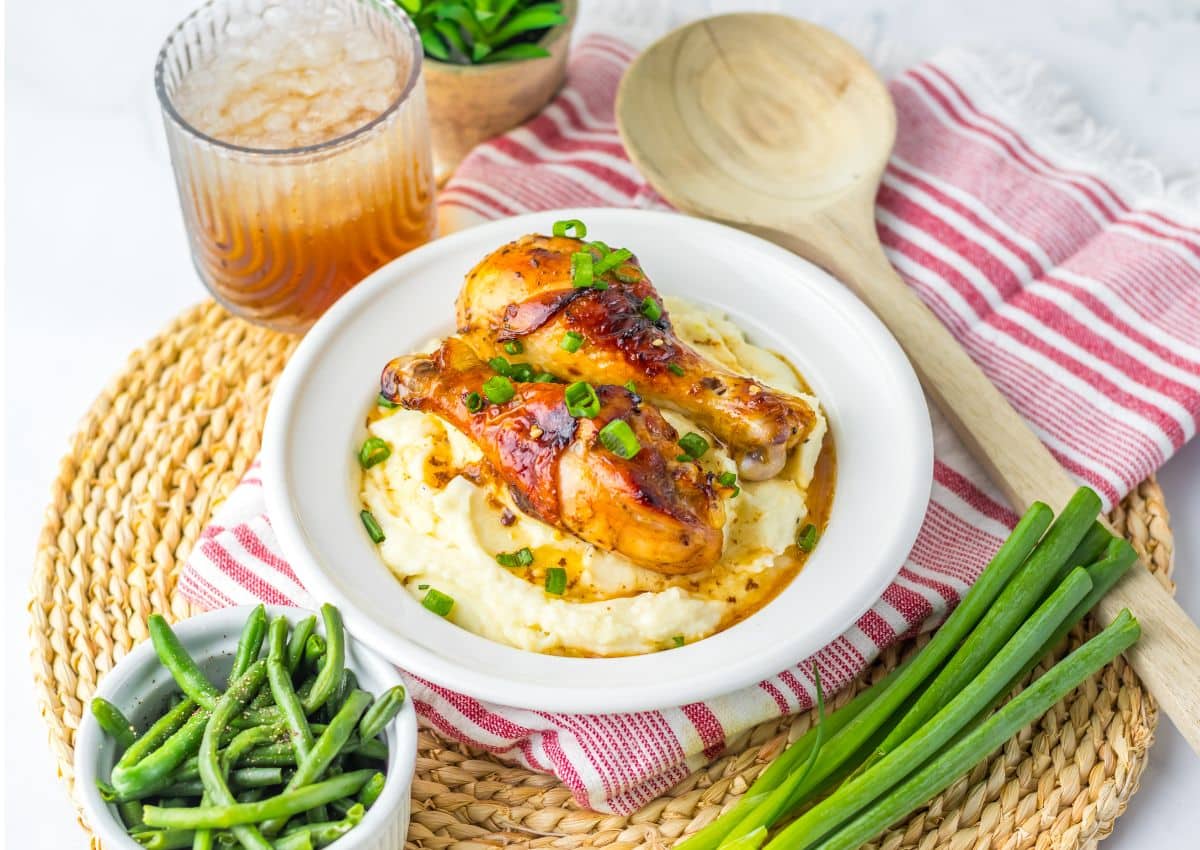 Two chicken drumsticks on top of a bed of mashed potatoes.
