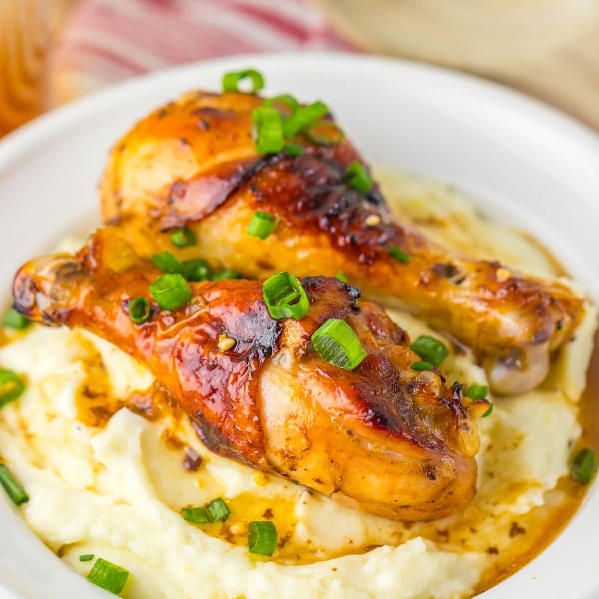 Two chicken drumsticks on top of a bed of mashed potatoes.
