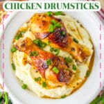 Two chicken drumsticks on top of a bed of mashed potatoes.