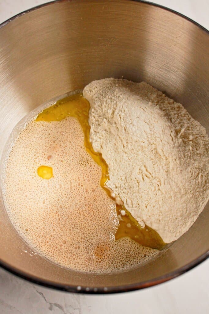 Wet ingredients and flour being mixed together in a stainless steel bowl.