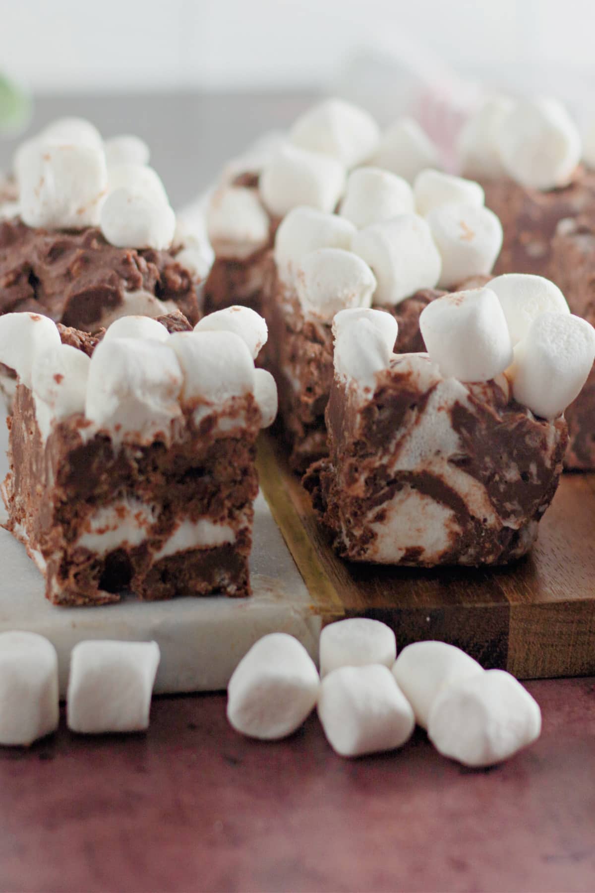 Pieces of rocky road candy bars on a wooden cutting board.
