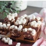 Pieces of rocky road candy bars on a wooden cutting board.