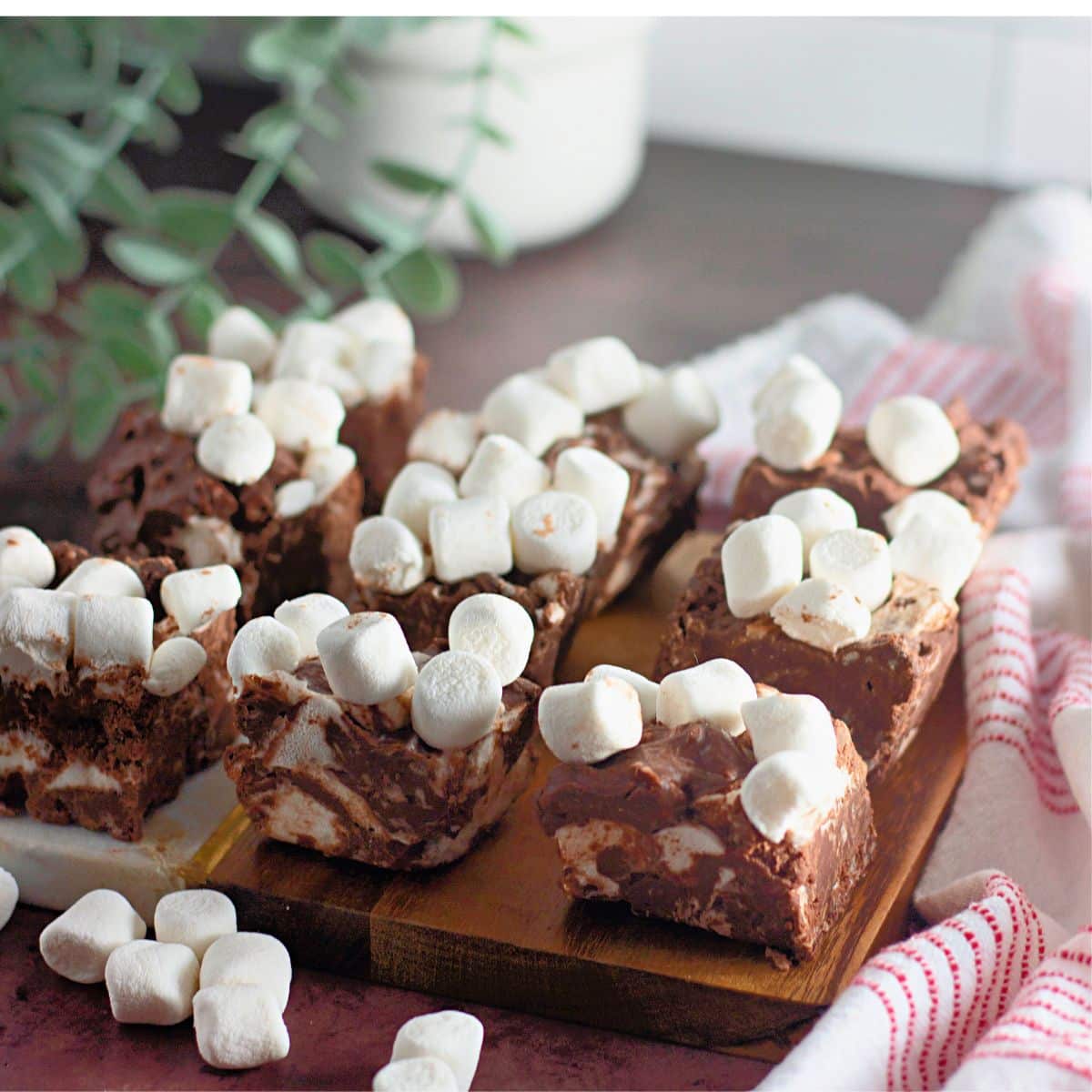 Pieces of rocky road candy bars on a wooden cutting board.