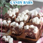Pieces of rocky road candy bars on a wooden cutting board.