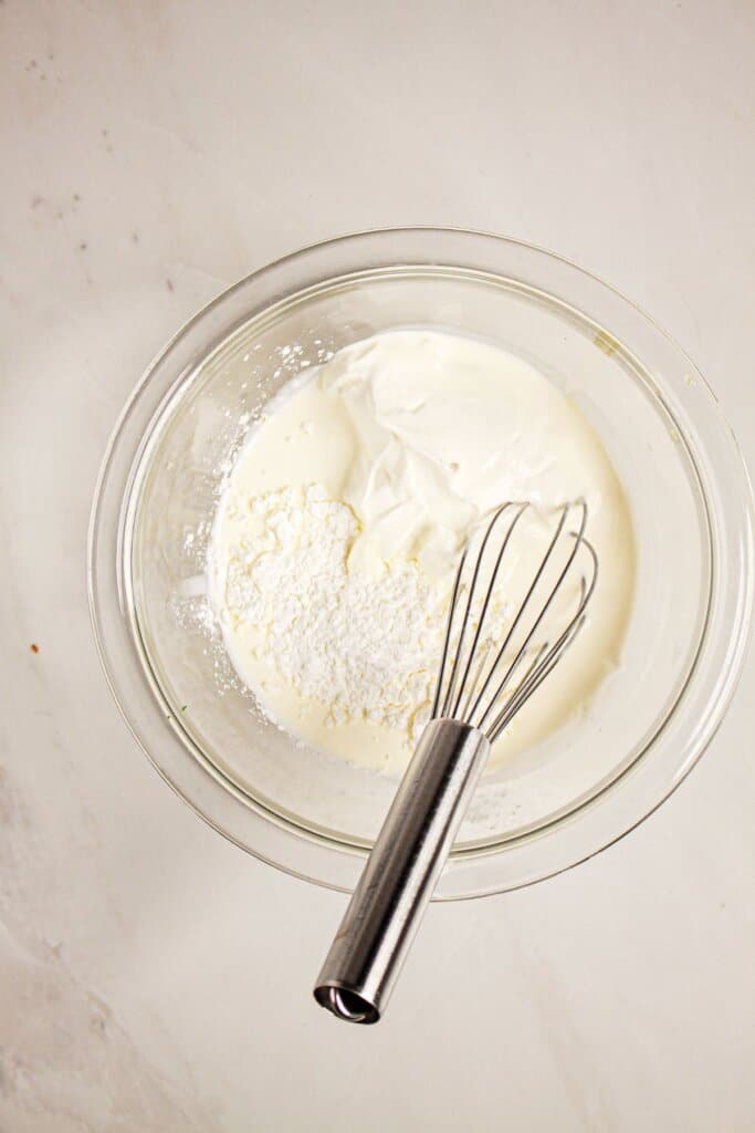 Sauce being mixed in a glass mixing bowl.