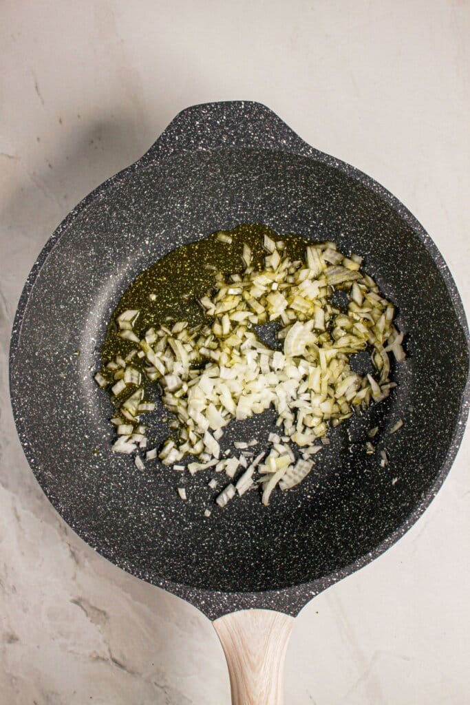 Onion being cooked in a skillet.
