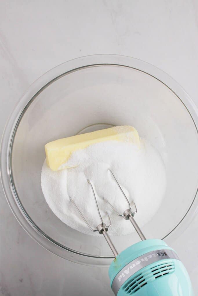 Butter and sugar being mixed in a glass bowl.