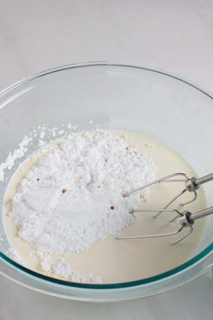Whipped cream being mixed in a glass bowl.