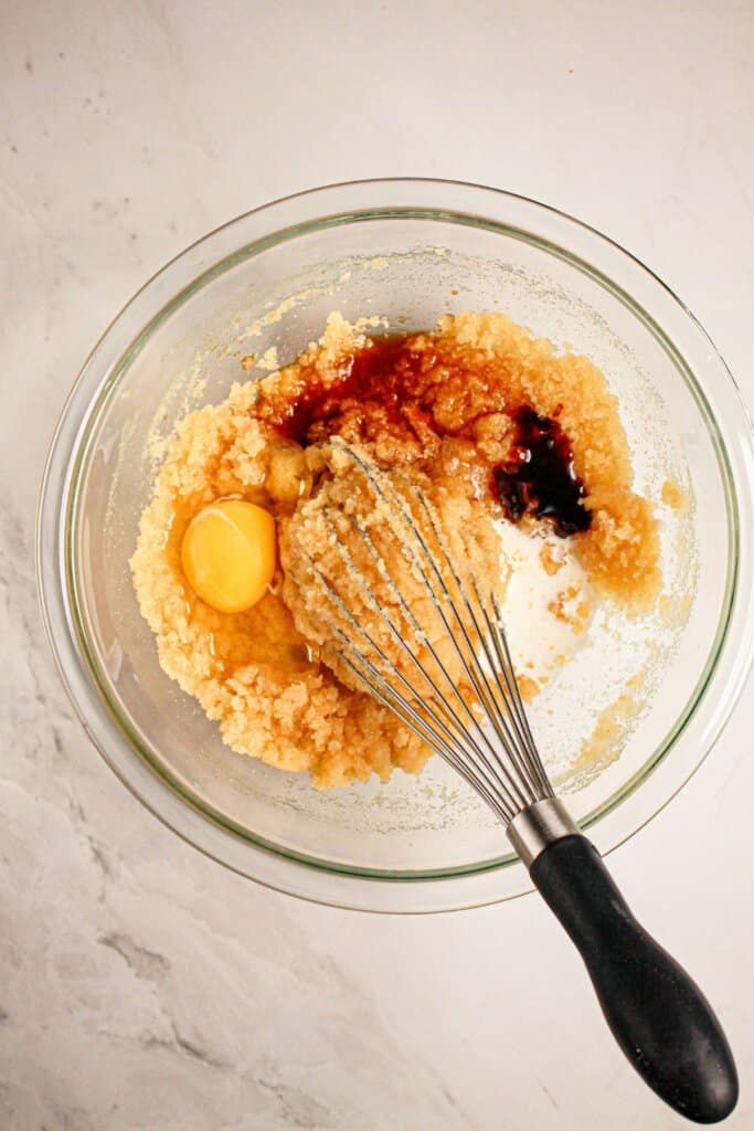 Eggs and vanilla being mixed into butter.