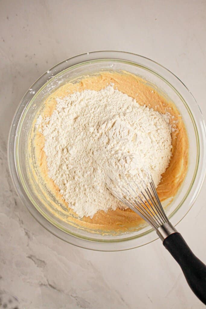 Flour being added to dough in a glass bowl.