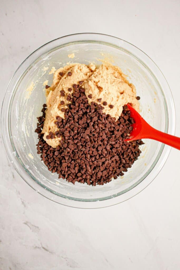 Chocolate chips being stirred into cookie dough.